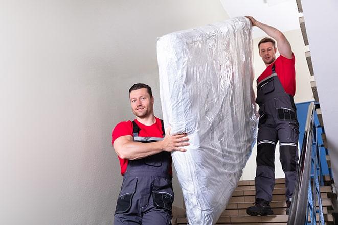 workers loading a box spring onto a truck for removal in Westminster